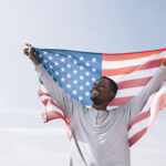 Smiling man holding U.S. flag, symbolizing success in the I-485 Application process