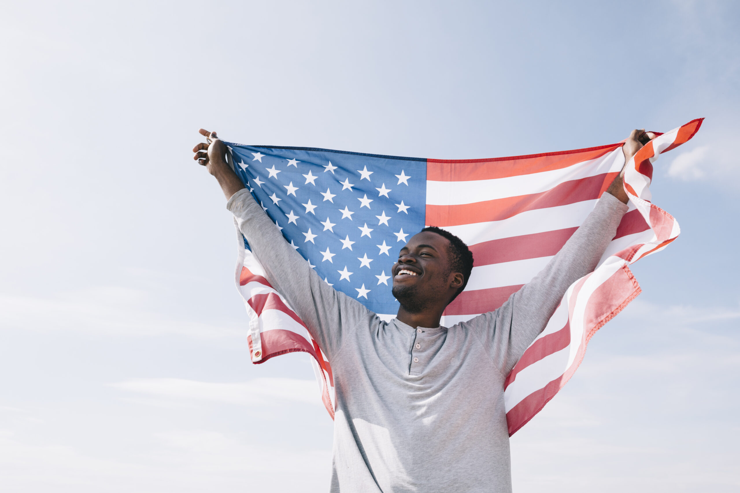 Smiling man holding U.S. flag, symbolizing success in the I-485 Application process